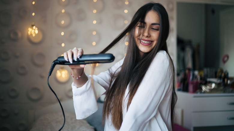 woman straightening hair with flatiron