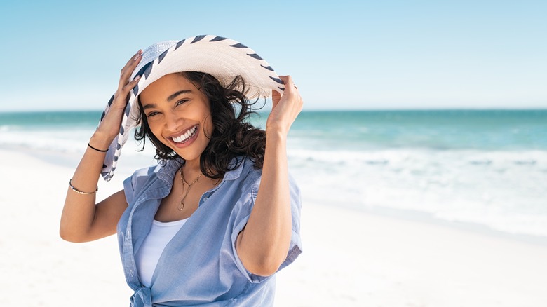 woman standing on beach wearing sun hat