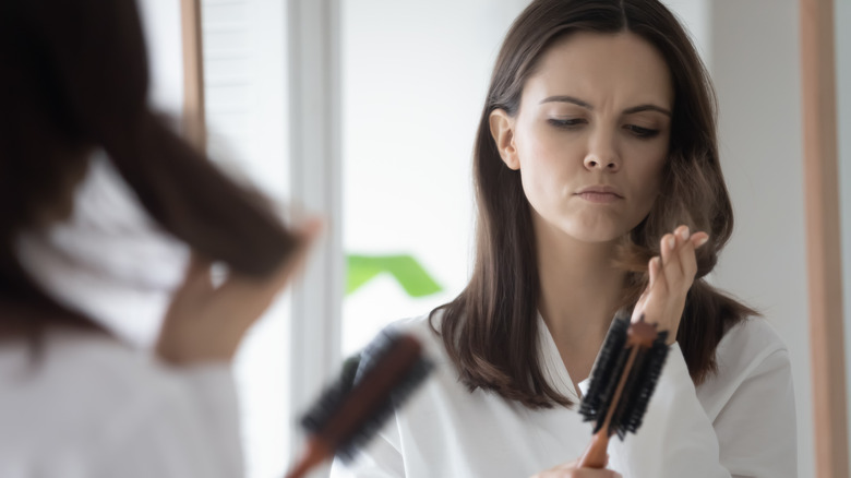 upset woman brushing hair with breakage