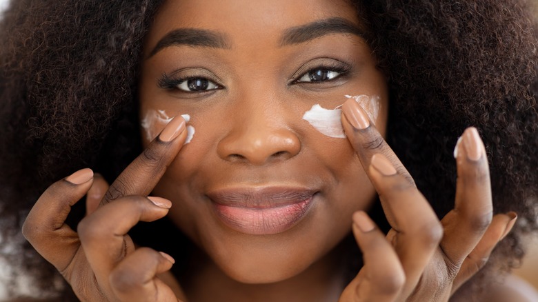 beautiful black woman applying sunscreen