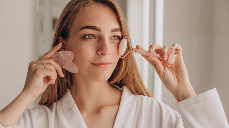 Woman uses jade roller on face