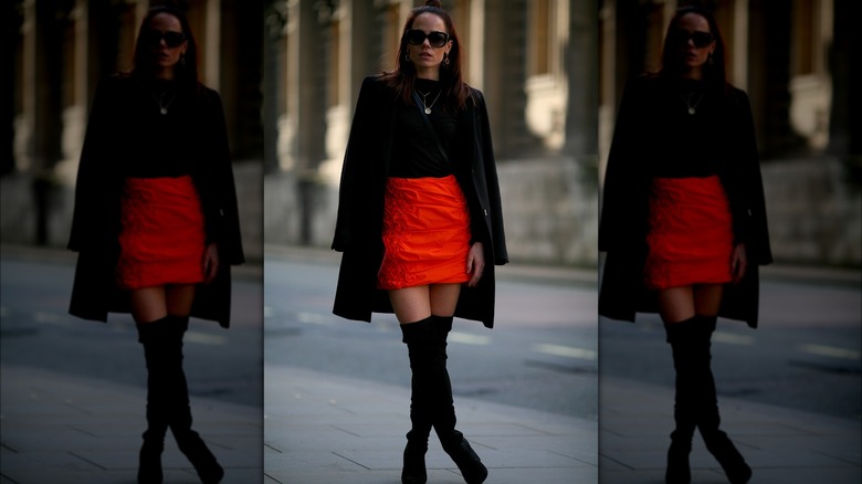 Woman wearing black coat and mini red skirt