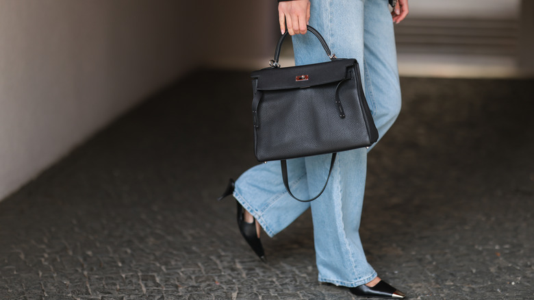 Woman wearing boyfriend jeans and carrying a black purse