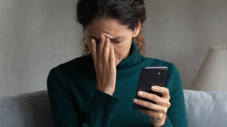 woman looking at her phone in stress