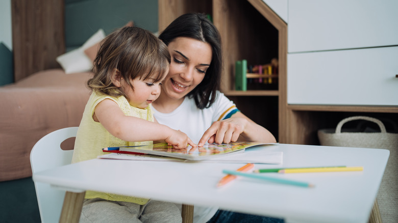 woman helping child color