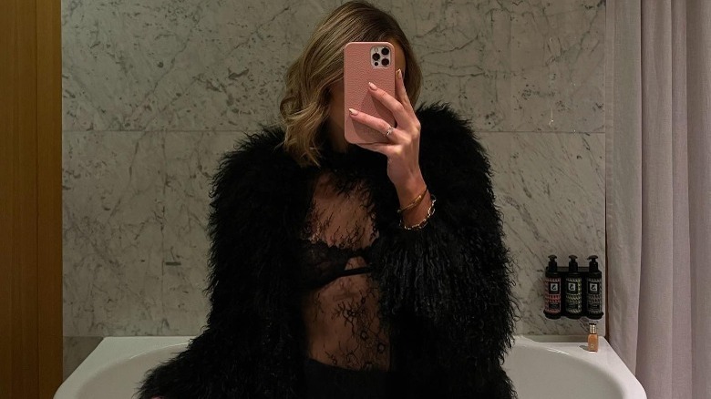 Woman wearing lace sheer top, fur jacket