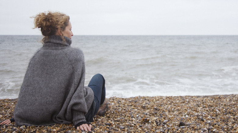 Thoughtful woman sitting by the ocean