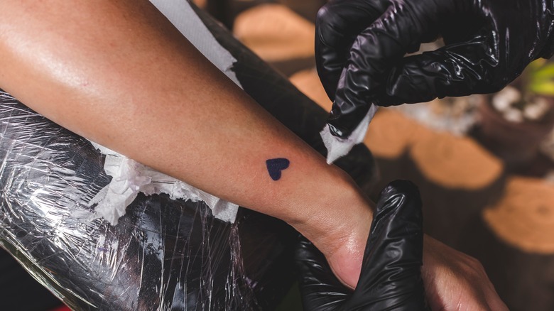 A woman getting a heart tattoo