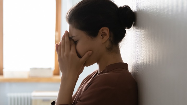 Stressed, overwhelmed woman covering her face