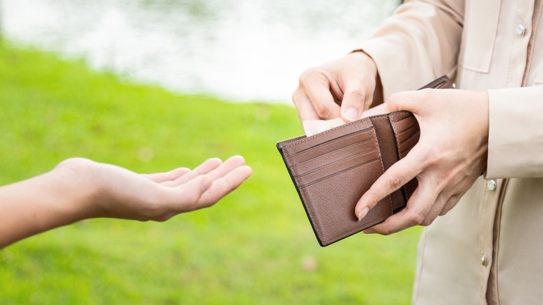 Hand outstretched for money from wallet