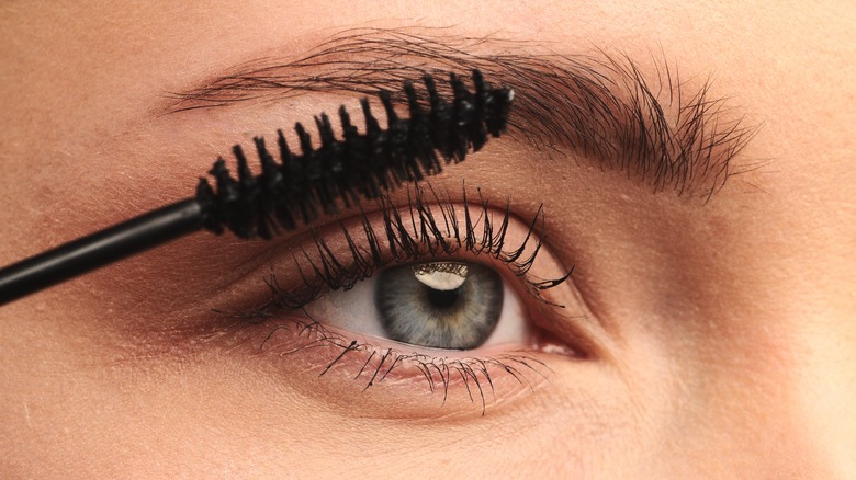 A woman applying mascara to her eyelashes