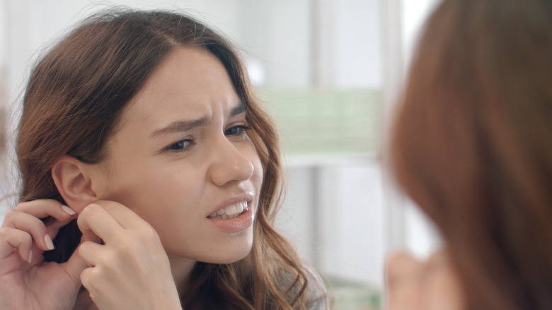 woman in pain touching ear