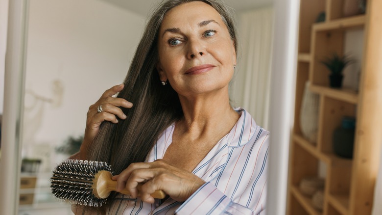 woman smiling and using round hairbrush