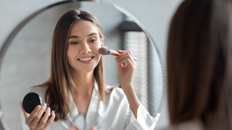 woman applying blush to cheek