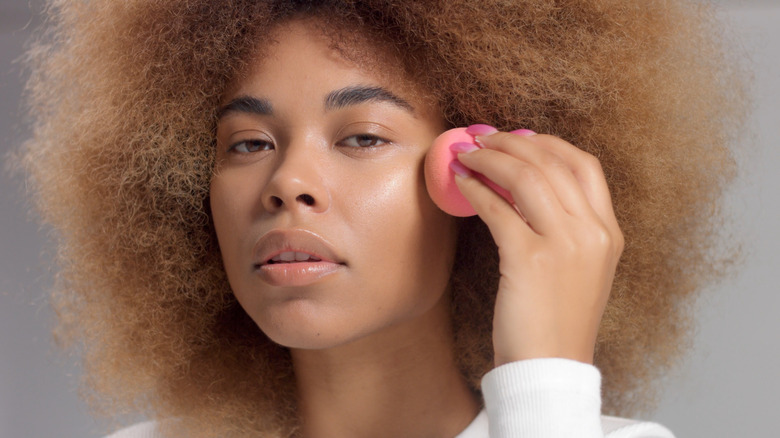 woman blending makeup with makeup sponge