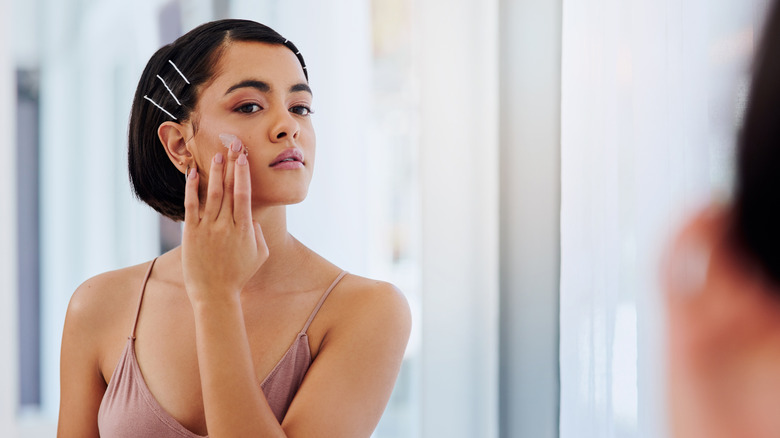 woman applying cream to cheek