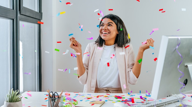 Woman throwing confetti at her desk