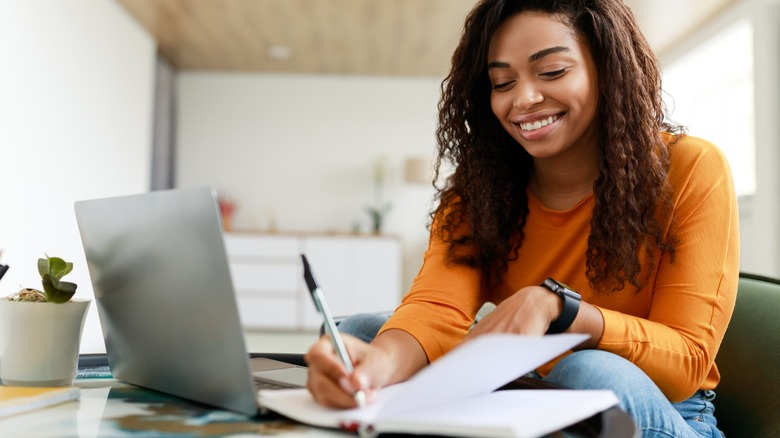 Smiling Black woman writing in notebook