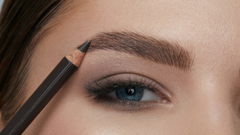 woman using eyebrow pencil