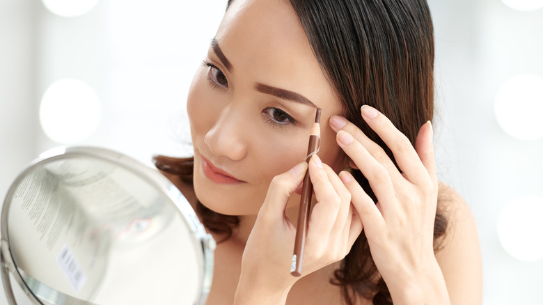 woman applying eyebrow pencil