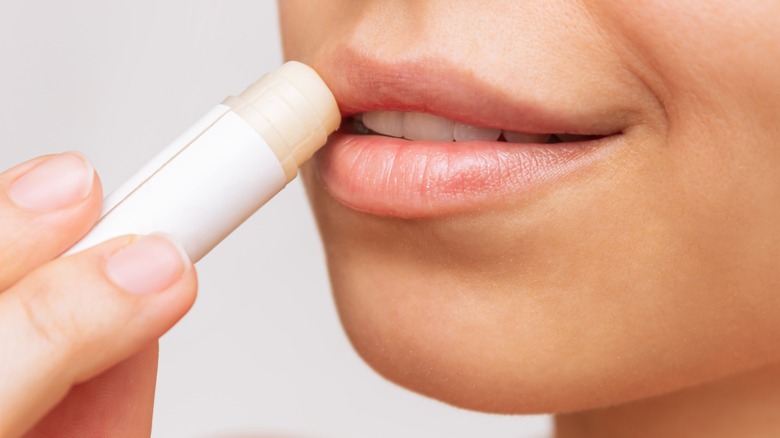 A woman putting lip balm on her lips