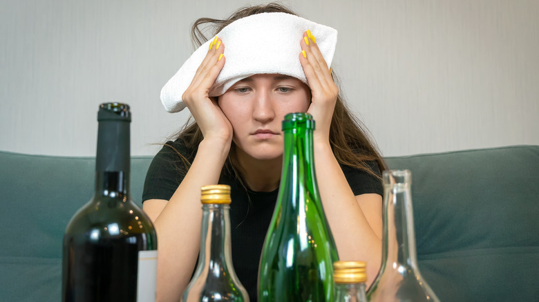Woman with headache looking at alcohol bottles