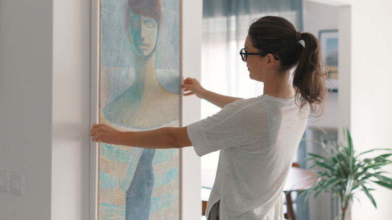 Woman hanging up artwork 