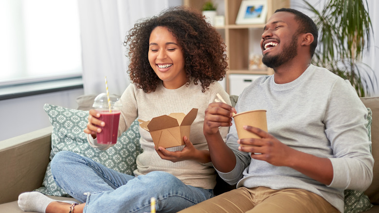 Couple eating takeout on the couch 