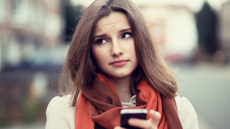 woman looking skeptically at phone