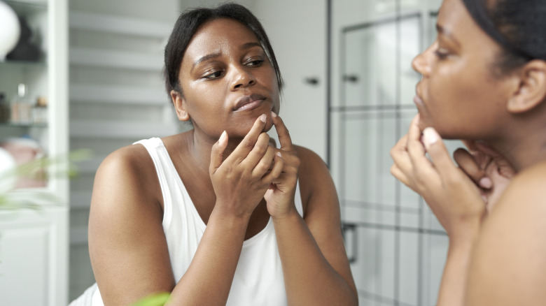 Young African American woman squeezing pimple 