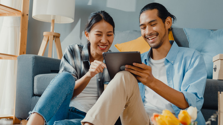 Asian couple smiling watching ipad