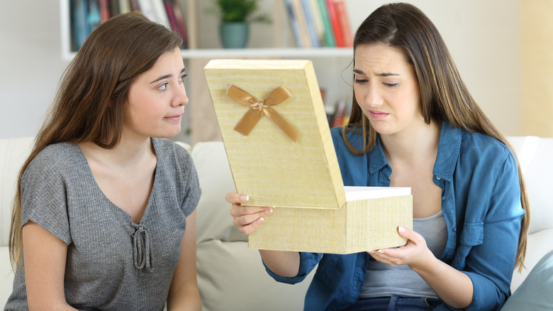 Uncomfortable guilty woman unwrapping gift