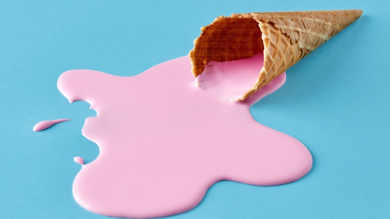 melted pink ice cream spills from the ice cream cone