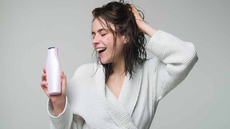 happy woman holding conditioner bottle