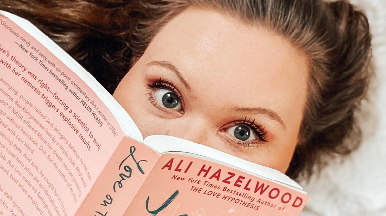 Excited woman reading Ali Hazelwood book
