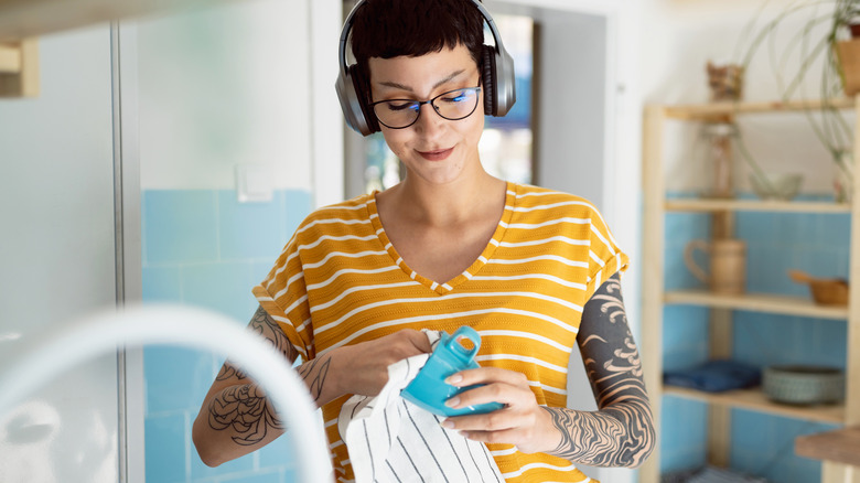 Woman washing dishes wearing headphones