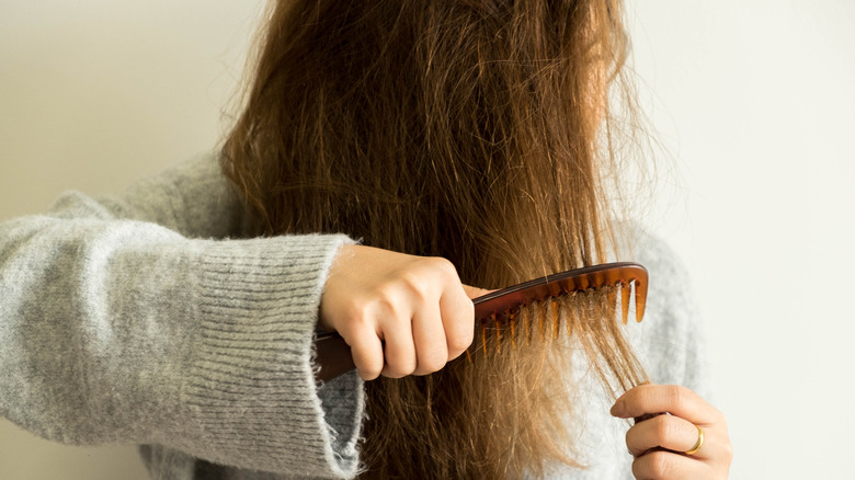 woman combing damaged hair 