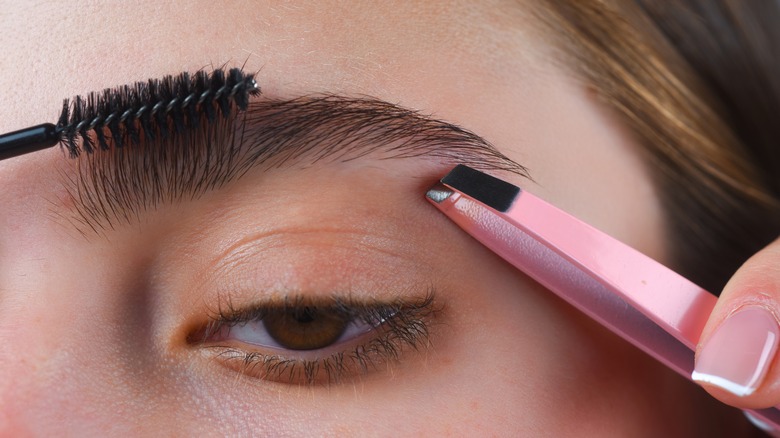 Woman plucking her eyebrows