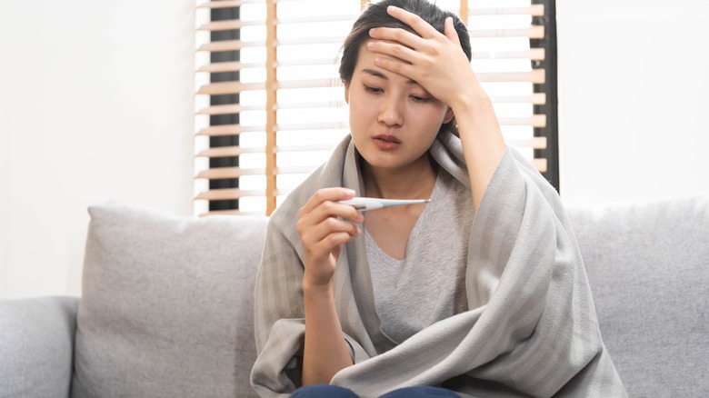 Sick woman looking at thermometer