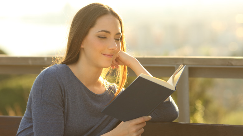 Woman reading book on bench