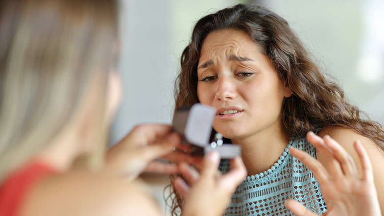 A woman feeling awkward about an engagement ring she just received