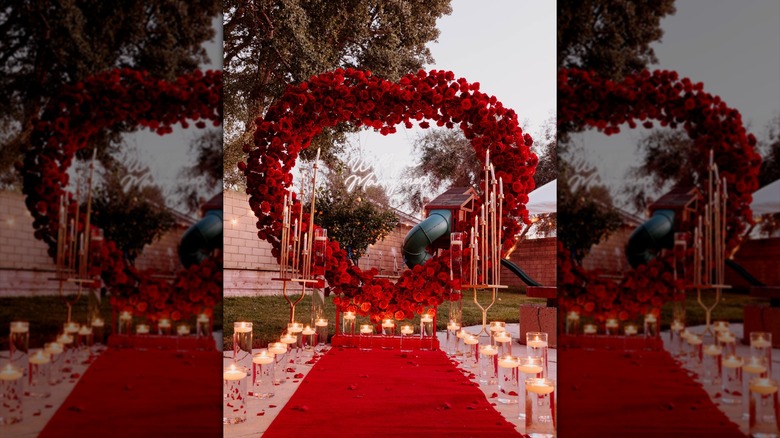 A proposal heart made up of red roses and set up with white candles