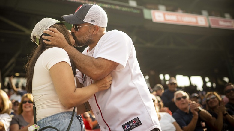 A couple getting engaged while spectators at a sports game