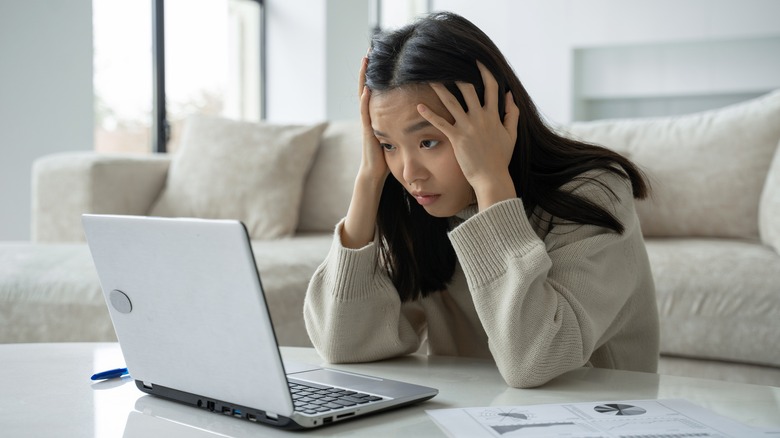 Woman overwhelmed sitting at laptop