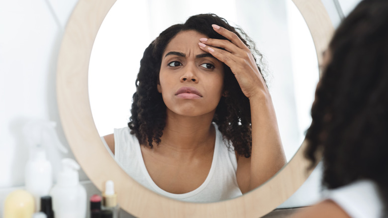 Woman examining wrinkles in the mirror