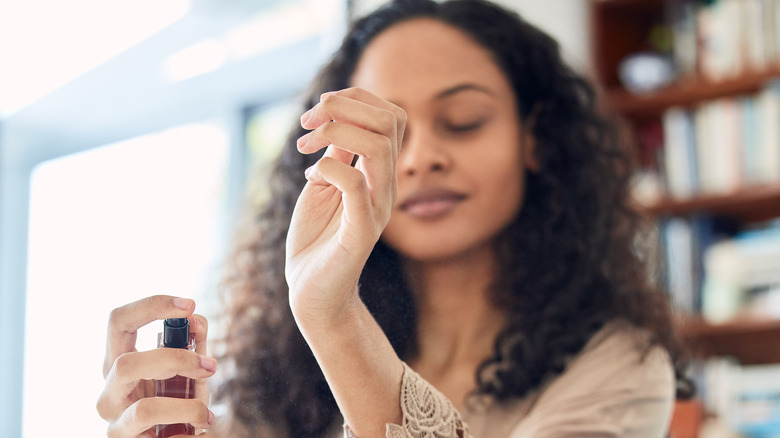 Woman spraying perfume on wrists