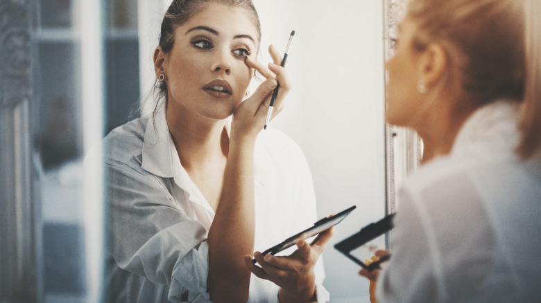 Woman doing her makeup in the mirror