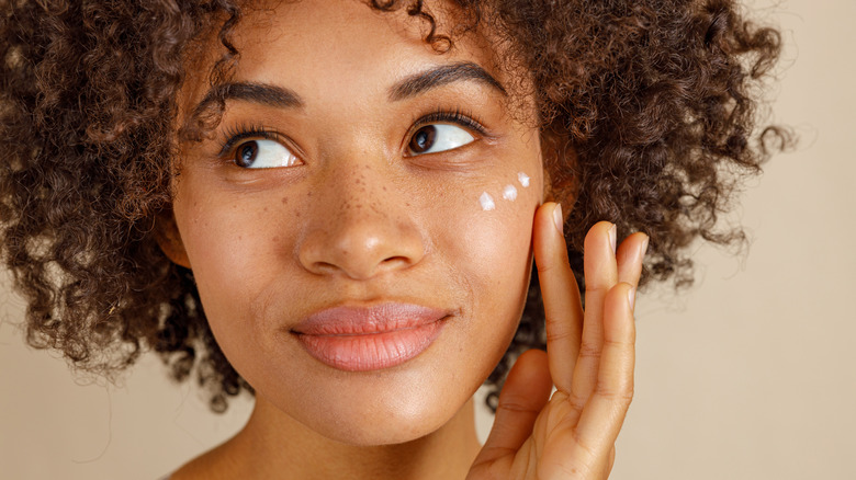 Woman applying moisturizer to her face