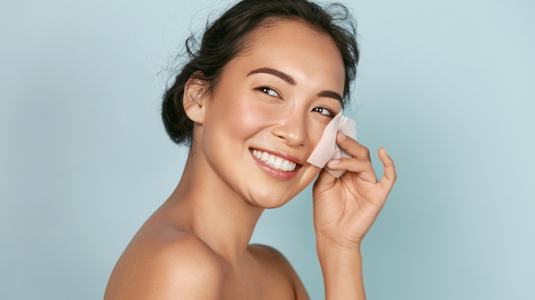 Woman with oily skin using blotting paper