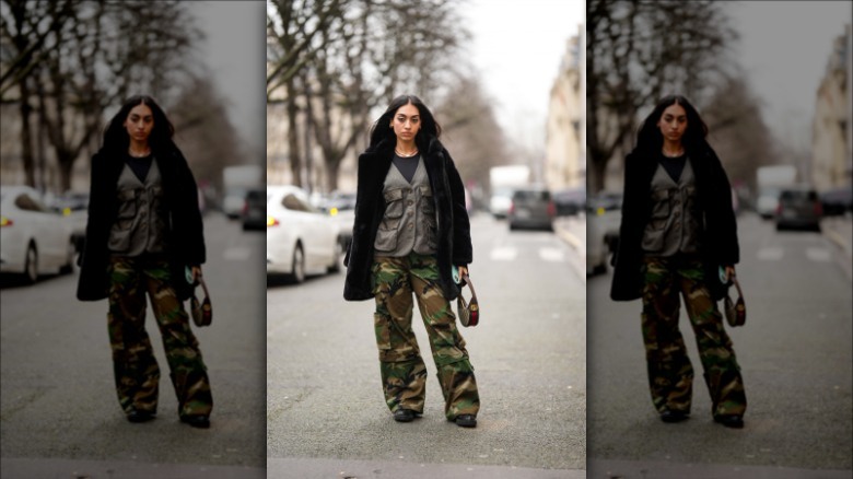 A woman wears a layered, camouflage outfit